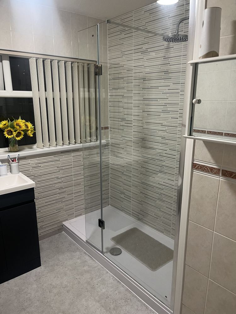 Walk-in shower enclosure with rainfall shower head and mosaic tiling