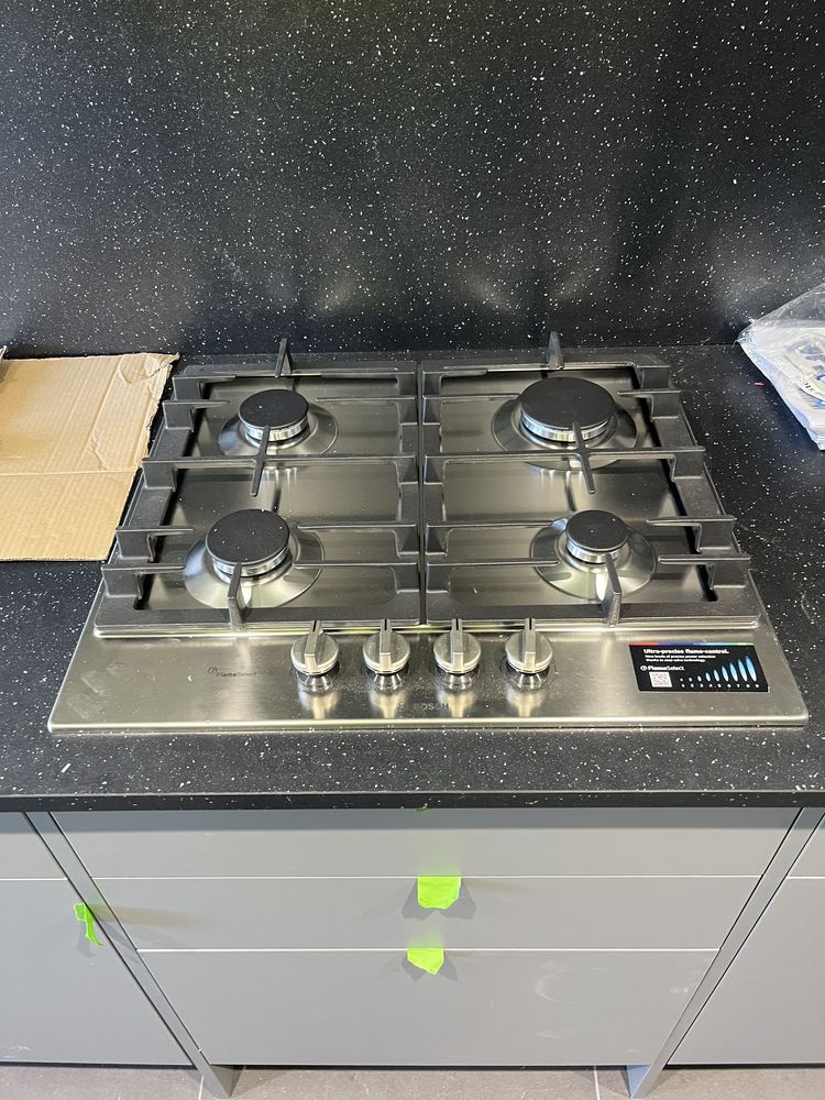 Stainless steel four-burner gas hob set into a dark sparkle worktop