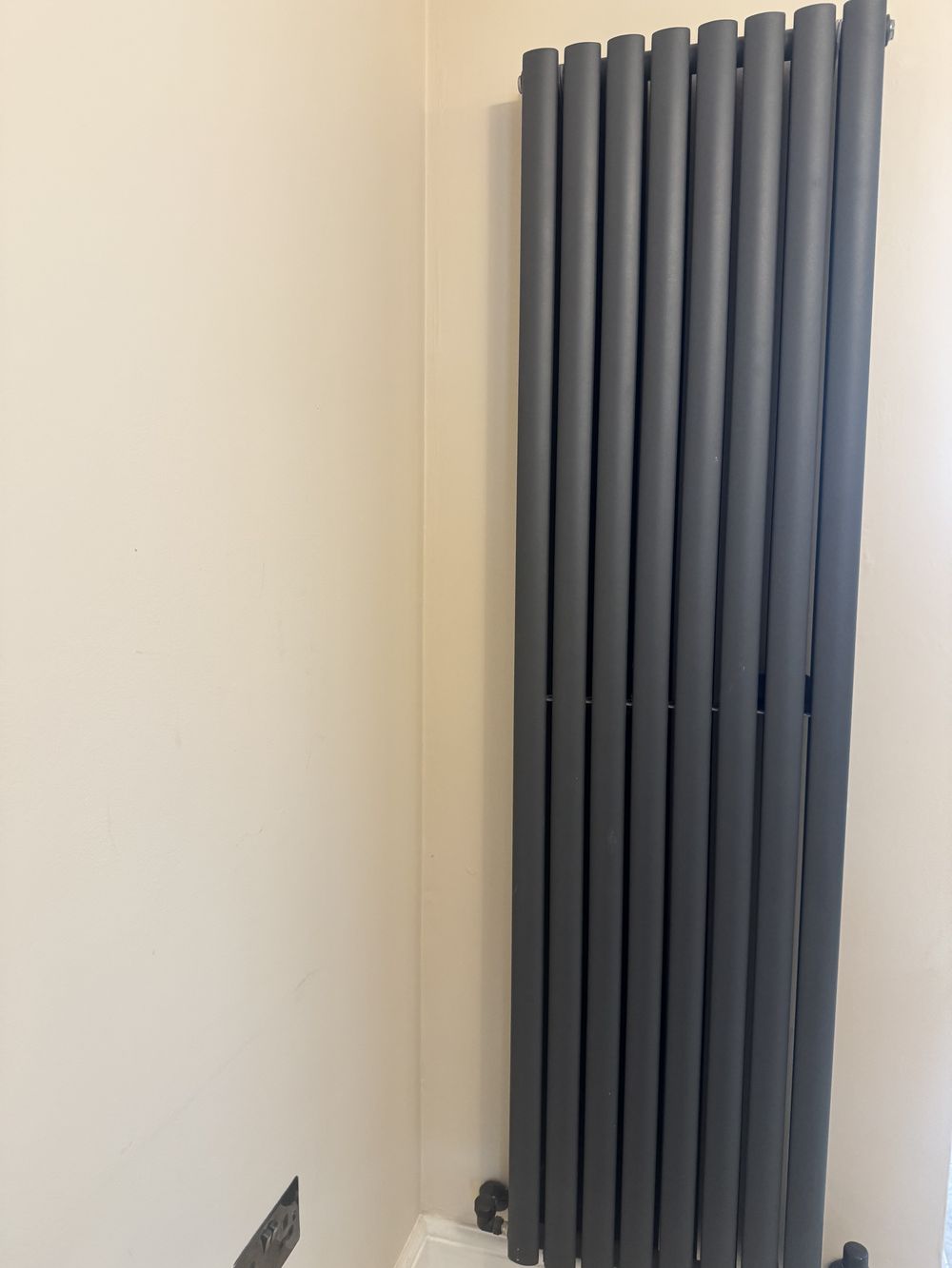 Anthracite vertical radiator in a corner with concealed pipework